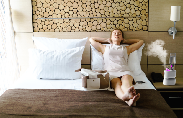 U100 ultrasonic travel humidifier BONECO woman relaxing hotel room with pink LED